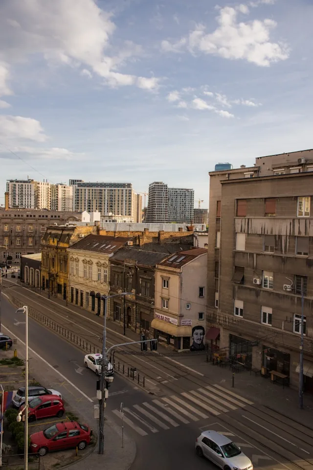 a soviet brutalist apartment building next to a hapsburg era townhouse in belgrade serbia