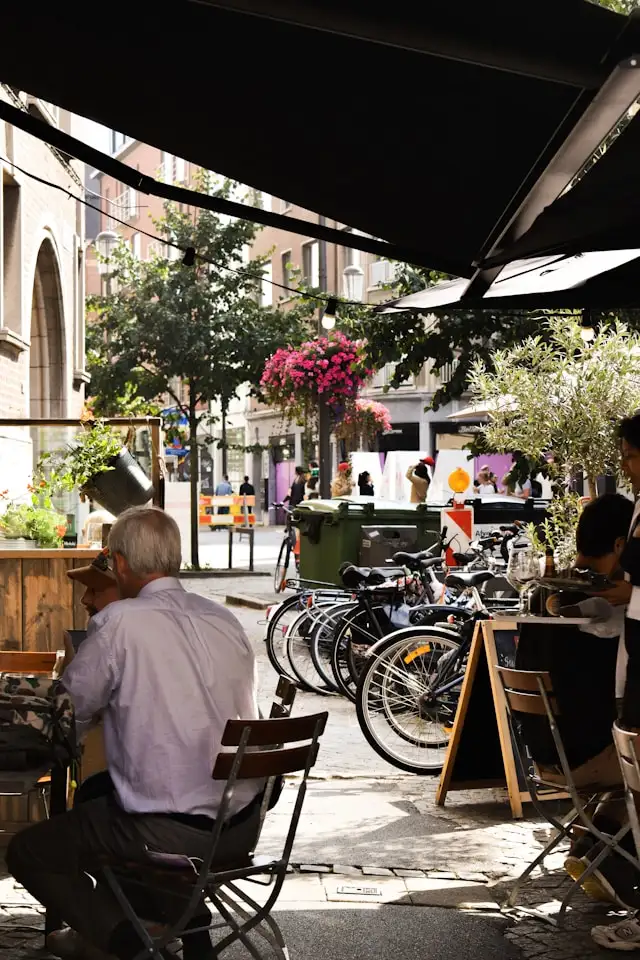 a man sitting outside a cafe under a canopy in antwerp belgium