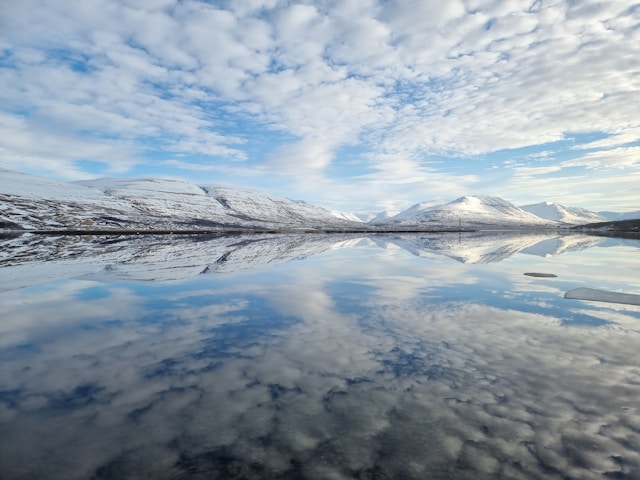 a lake in iceland with snow covered mountains in the background