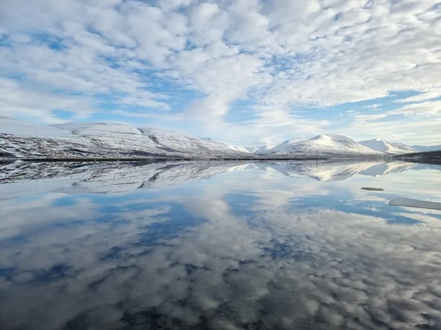 a lake in iceland with snow covered mountains in the background