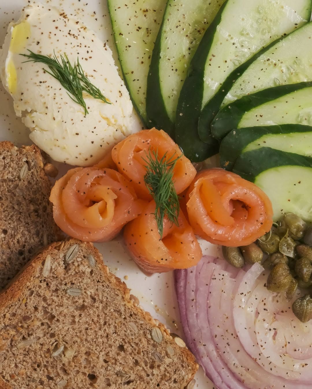 Fresh smoked salmon rolls with health bread, cream cheese, cucumber, capers and red onions