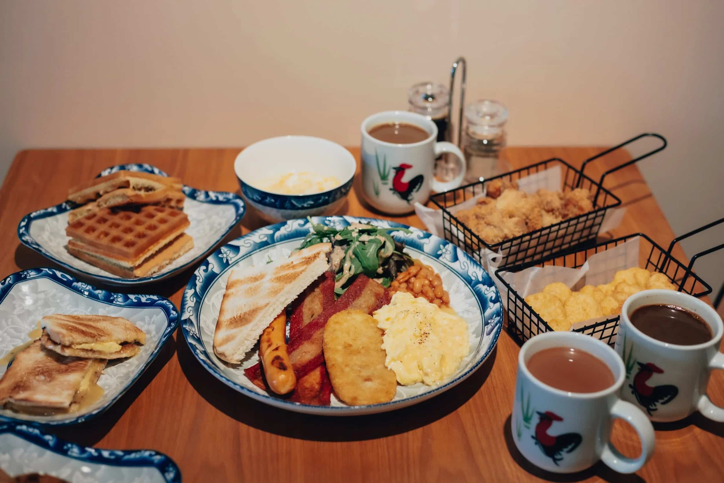 A selection of breakfast including waffles, kaya toast and fry up, kopi