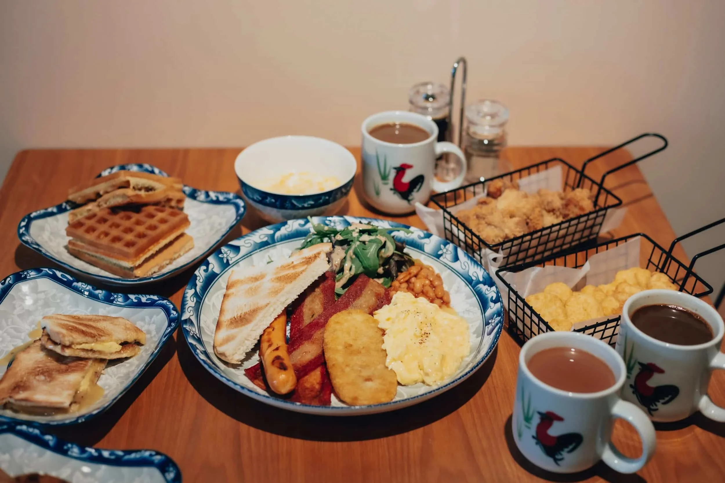 A selection of breakfast including waffles, kaya toast and fry up, kopi
