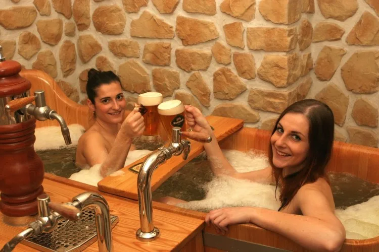 two women in a spa tub filled with beer raise pint glasses at a beer spa in prague czech republic