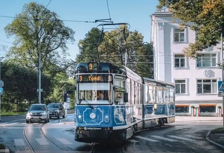 A tram on a street with cars next to a high-rise building - day trip from helsinki to tallinn