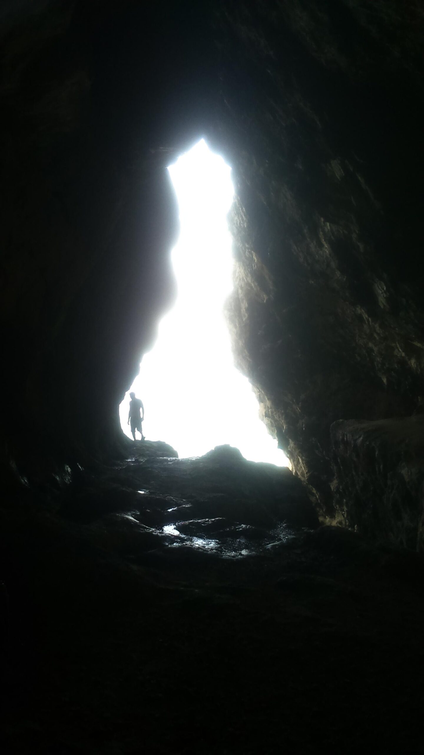 A person standing at the entrance of a cave