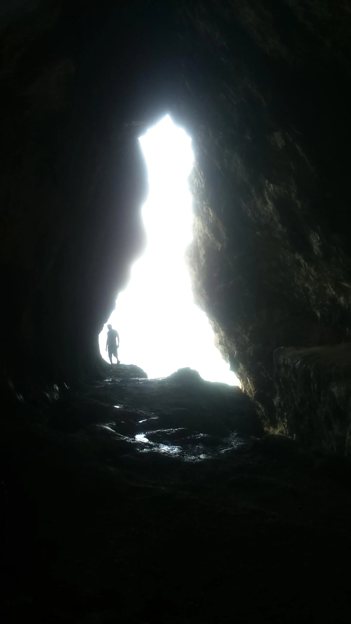 A person standing at the entrance of a cave