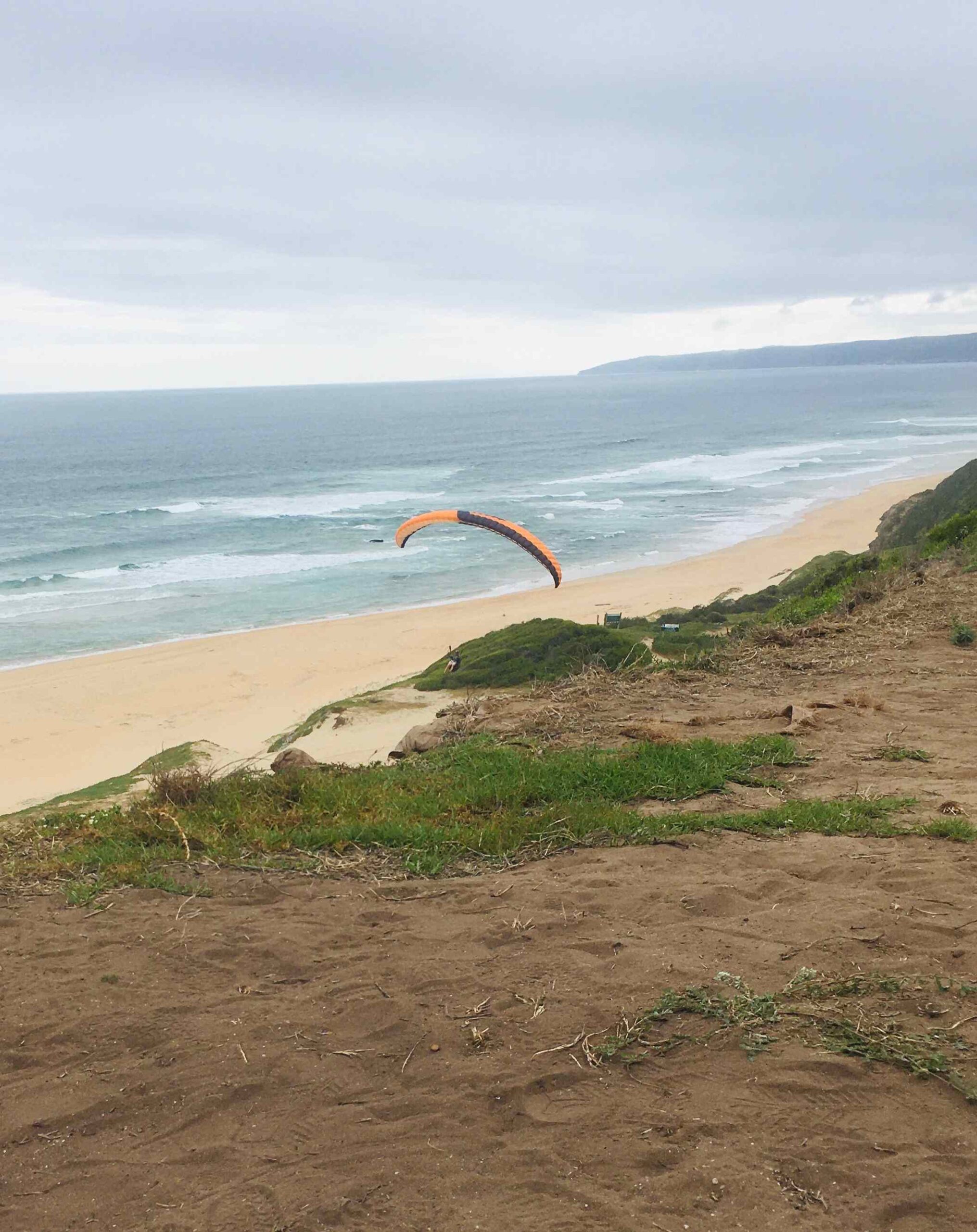 Paragliding over dunes by the ocean