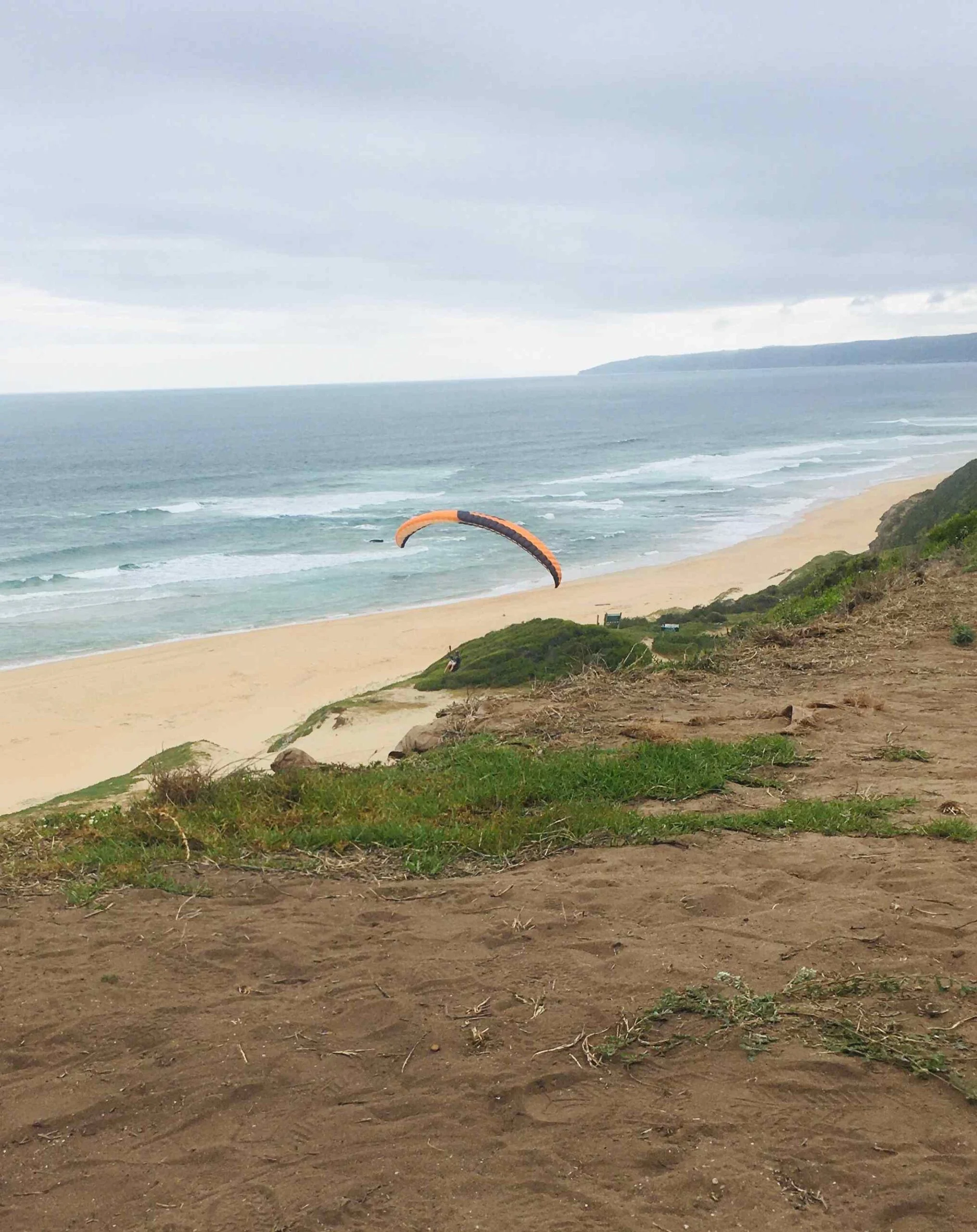 Paragliding over dunes by the ocean