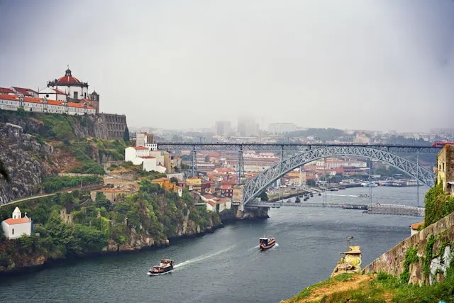 two rabelo boats sailing under luis I bridge in porto portugal on a six bridges cruise