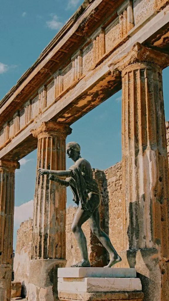 a statue outside a ruined temple in the lost city of pompei near naples italy a highlight of a 3 months in europe itinerary
