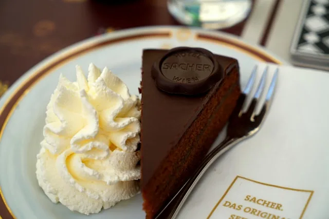 sacher torte with cream on a white plate with a gold rim