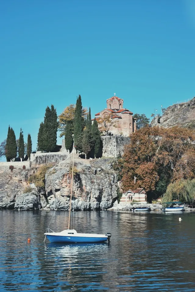 a small boat sits in front of the church of st john at kaneo on lake ohrid in north macedonia 