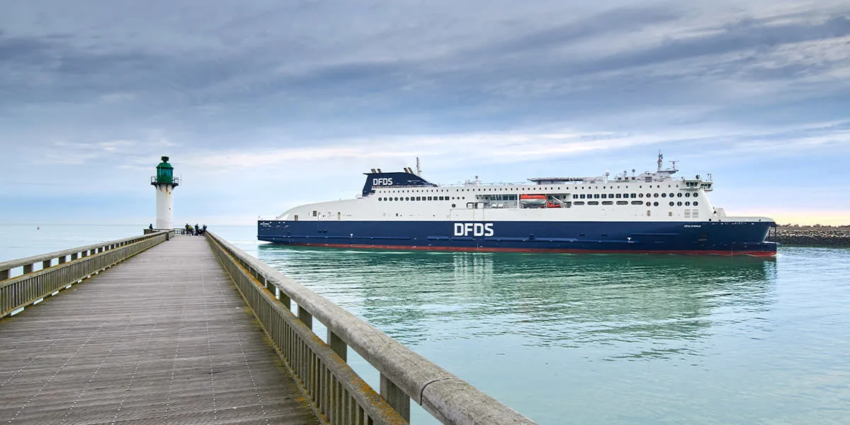 a dfds seaways ferry passing a lighthouse at the entrance to the port of calais on the cote d'opale in northern france
