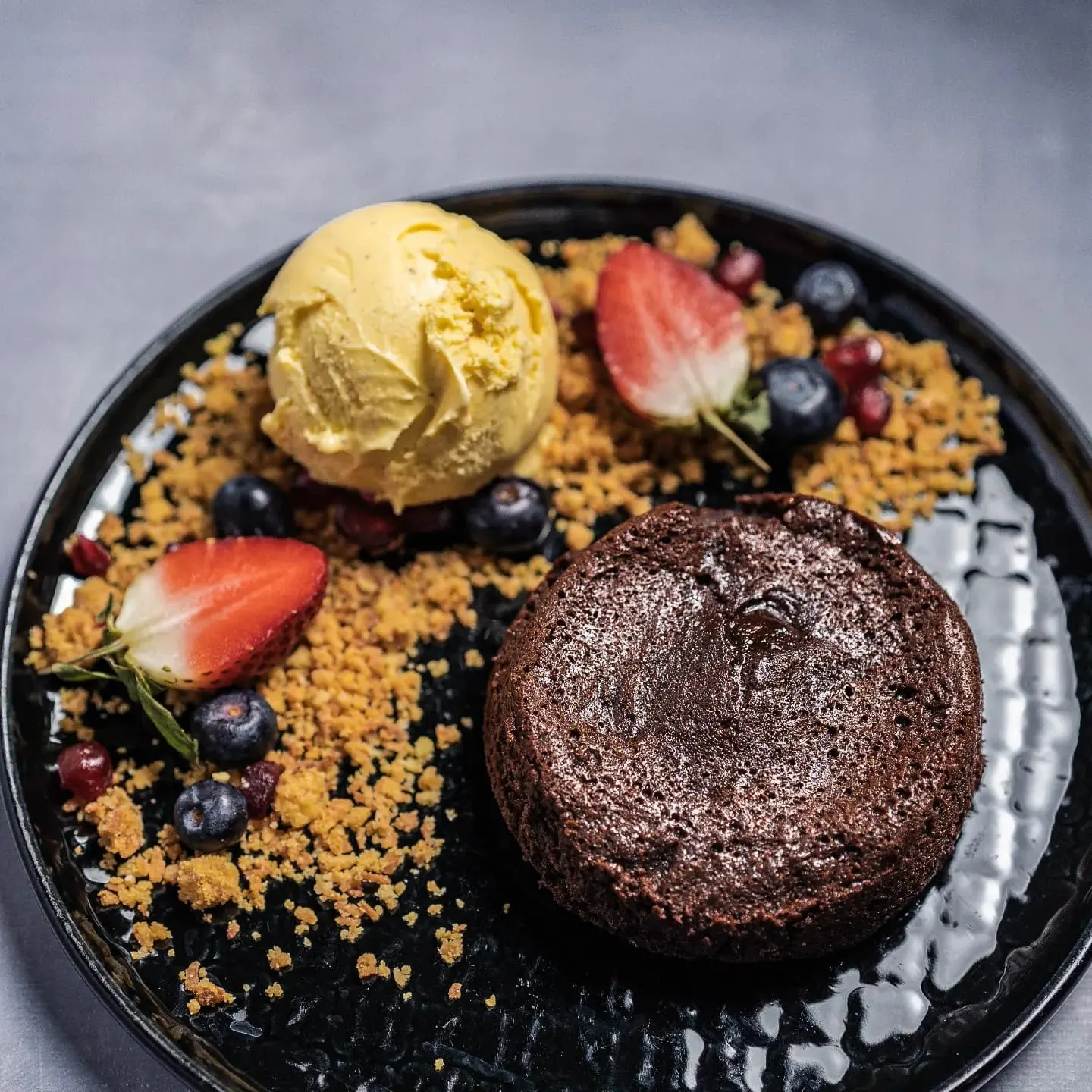 chocolate fondant with ice cream and biscuit crumb on a black plate from literacka one of the best restaurants in gdansk