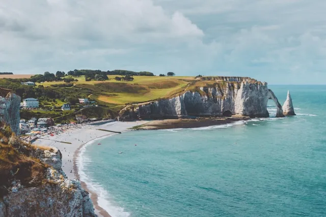 a beach in normandy northern france with a rocky outcrop and sea arch in the background