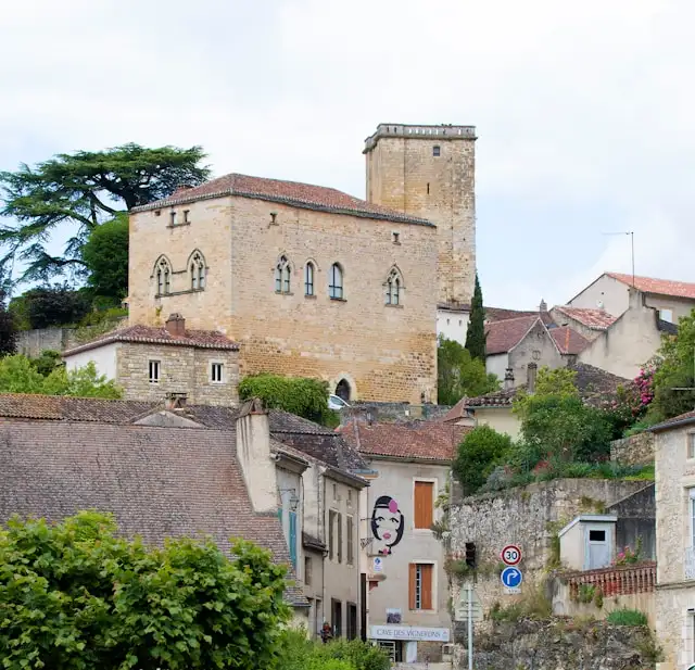 a castle on a hillside in northern france with road signs in the foreground