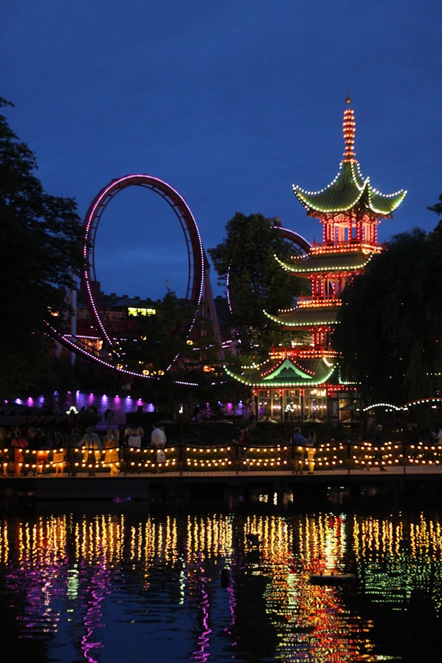 a japanese pagoda and a rollercoaster at night in tivoli gardens copenhagen denmark