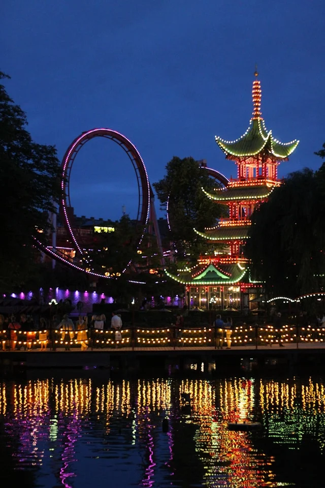 a japanese pagoda and a rollercoaster at night in tivoli gardens copenhagen denmark