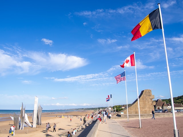 german, canadian and u.s. flags fly above a d-day memorial on a beach in northern france