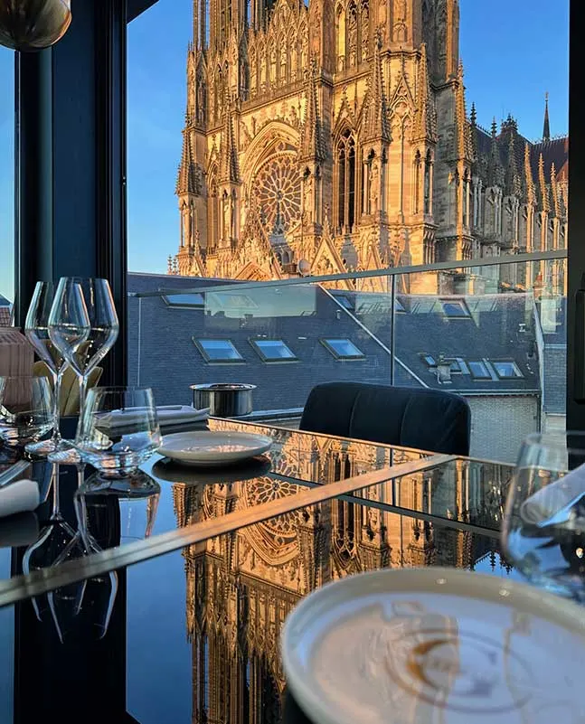 wine glasses and tableware on a table overlooking a cathedral at restaurant gabrielle in reims france