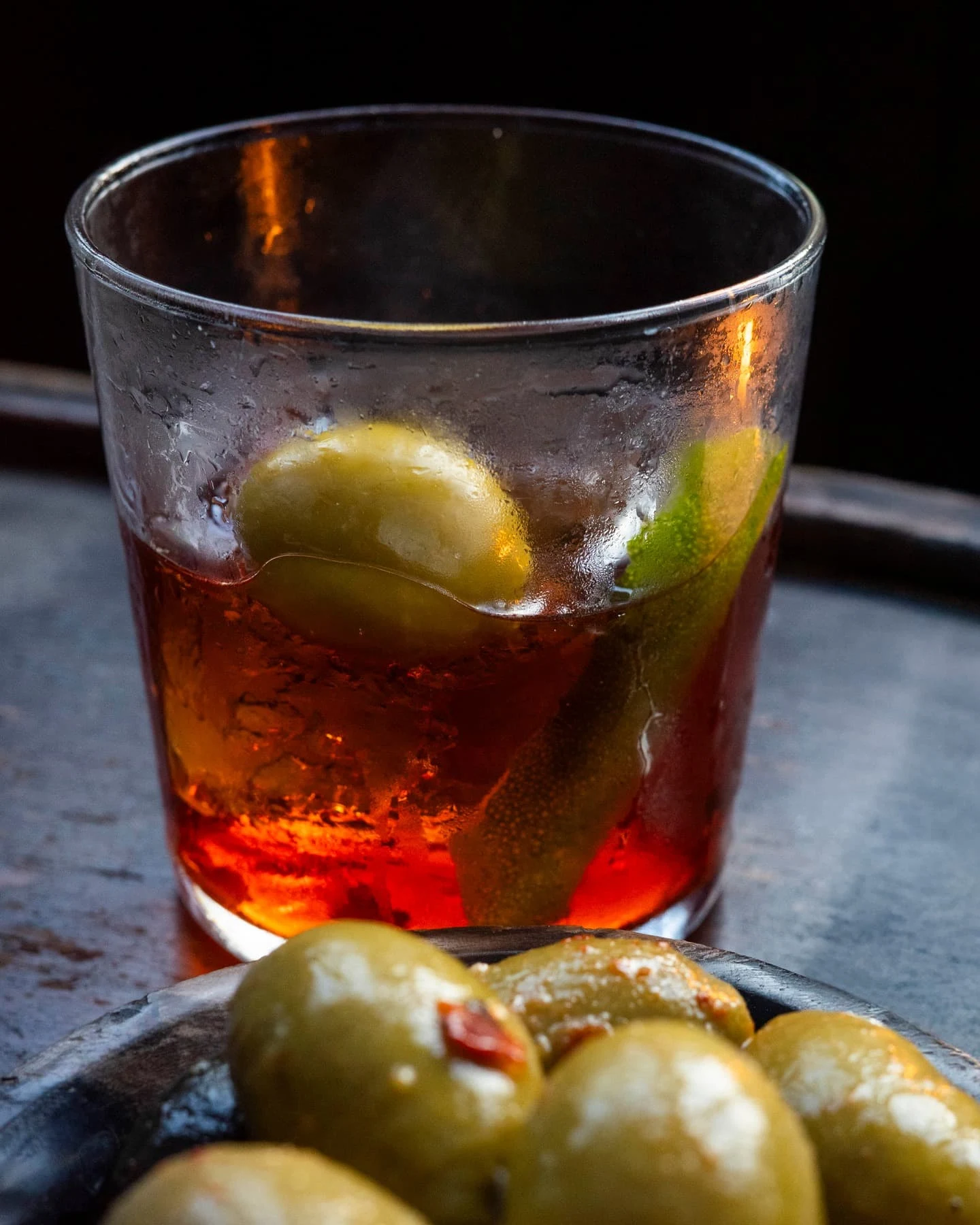 The specialty negroni cocktail served with green olives