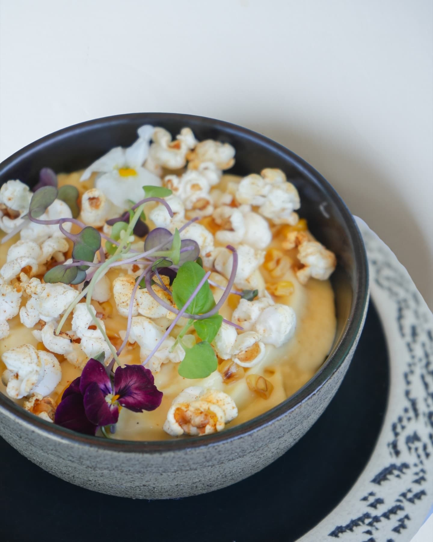 Expect playful dishes like this soup topped with popcorn