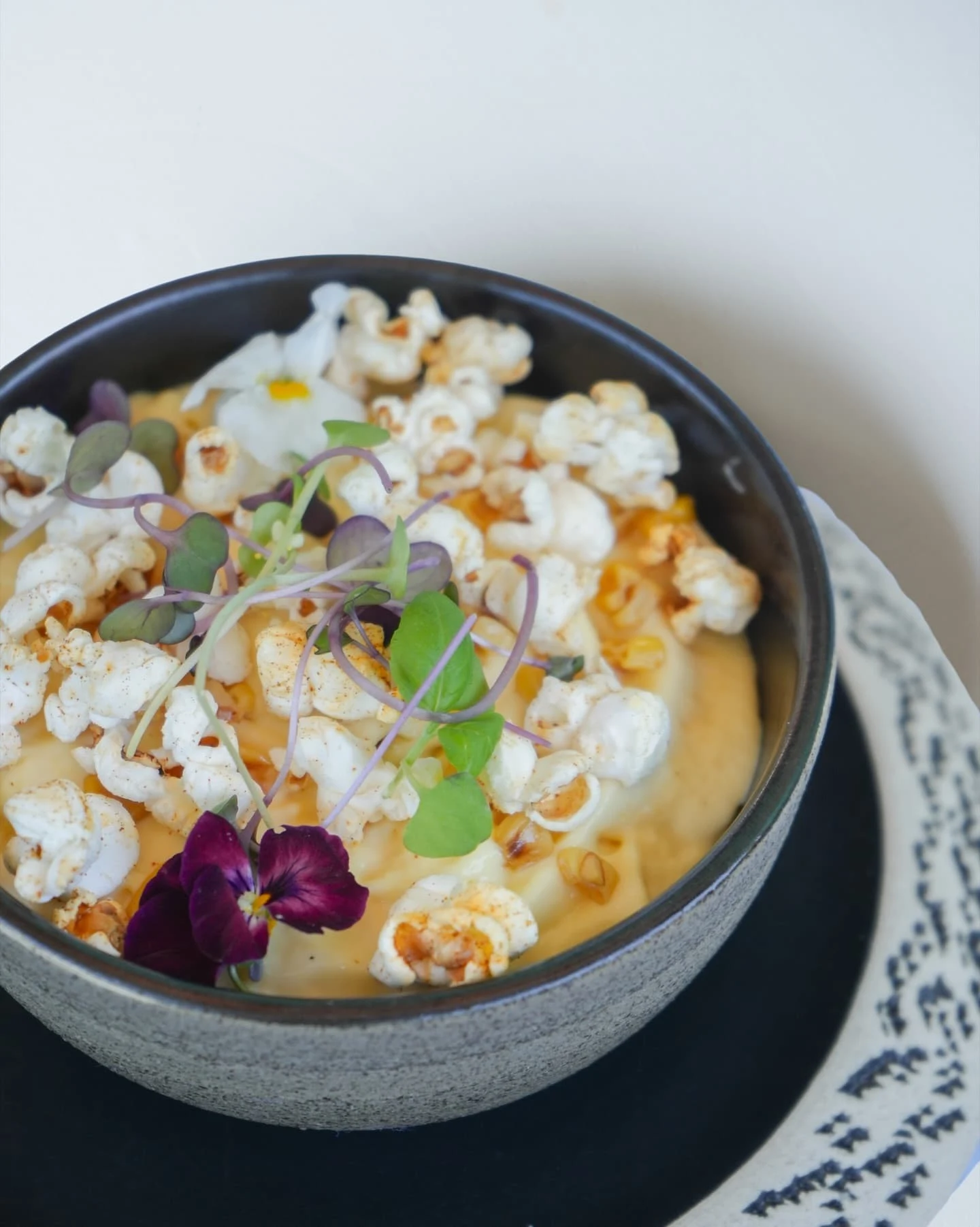 Expect playful dishes like this soup topped with popcorn