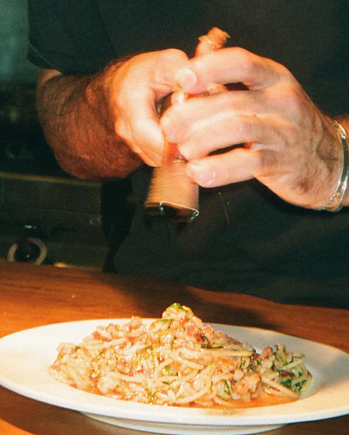 Pasta on the pass with chef doing finishing seasoning touches
