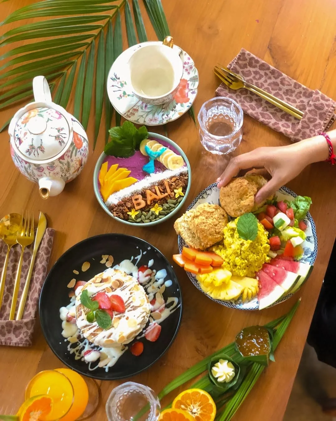 Food options including a Bali smoothie bowl, pancake stacks, scones, fresh fruit and a pot of tea
