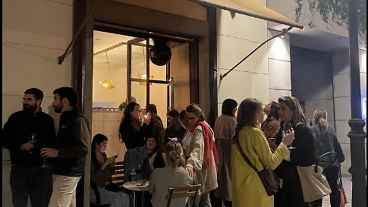 people standing on the street outside la alquimia wine bar in madrid spain