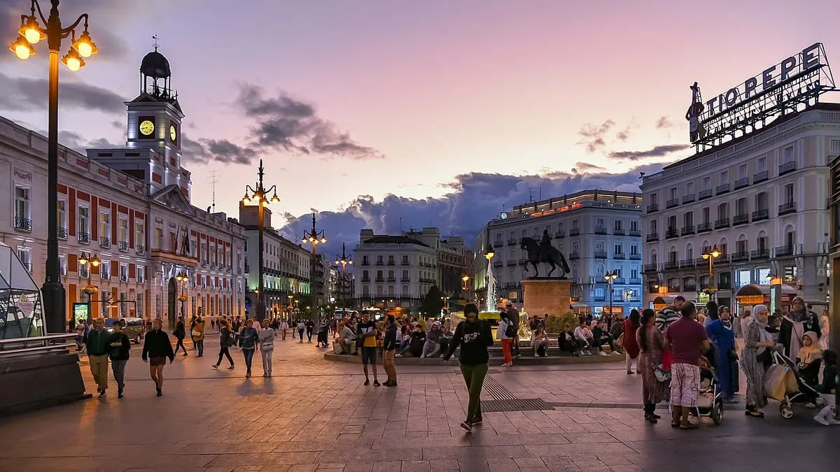 people walk around puerta del sol plaza one of the best areas to stay in madrid spain at dusk