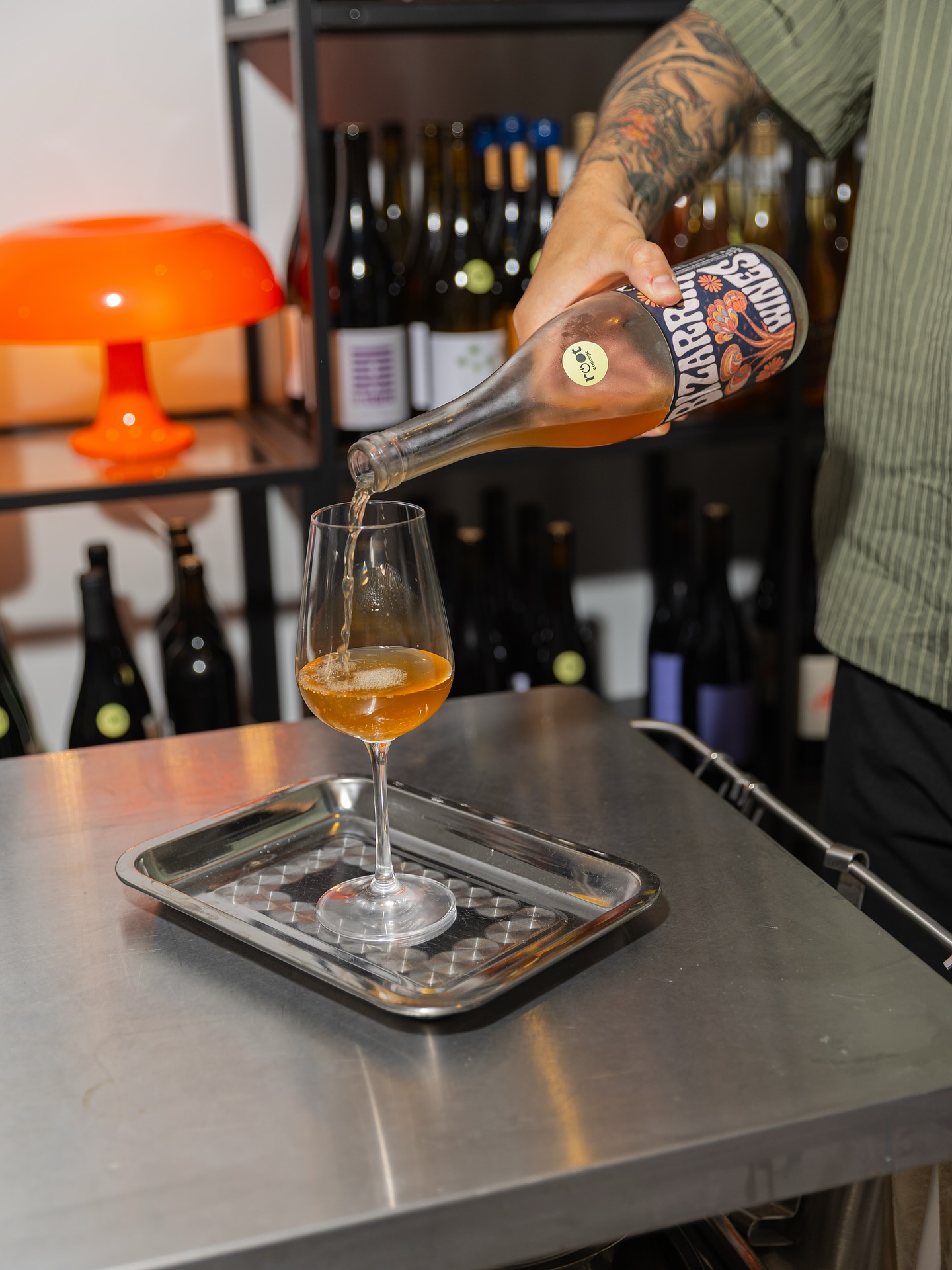 a sommelier pours orange wine into a glass on a silver tray at root concept in madrid spain