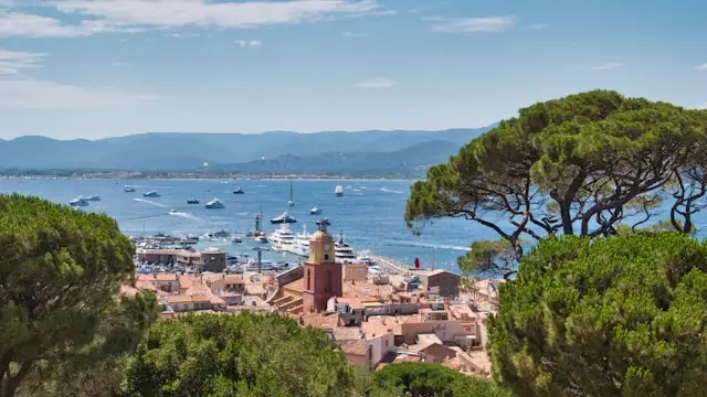yachts on the mediterranean ocean with red brick rooftops in the foreground in saint-tropez france