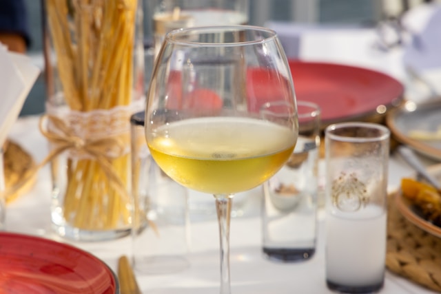 a glass of spanish white wine on a table with breadsticks in the background