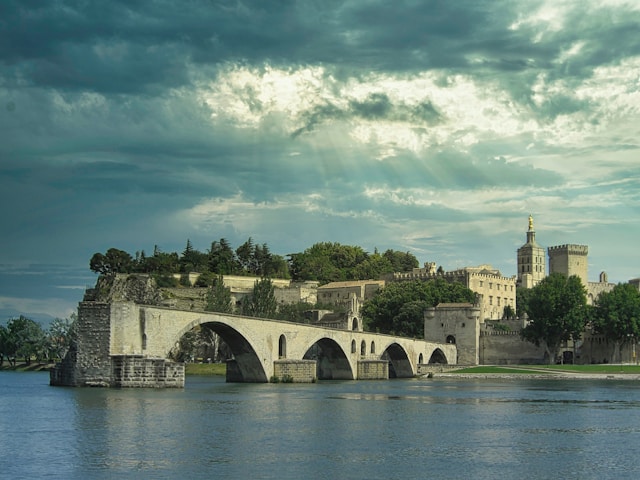 pont sainte-benezet is a ruined medieval bridge in avignon france with the palace of the popes in the background on a stormy night