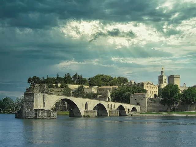 pont sainte-benezet is a ruined medieval bridge in avignon france with the palace of the popes in the background on a stormy night