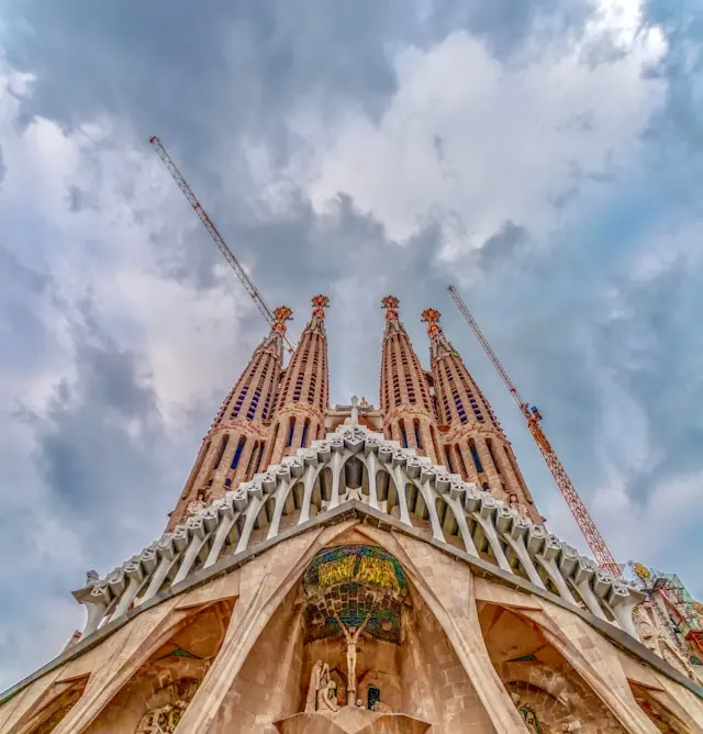 the sagrada familia cathedral in barcelona spain with cranes in the background