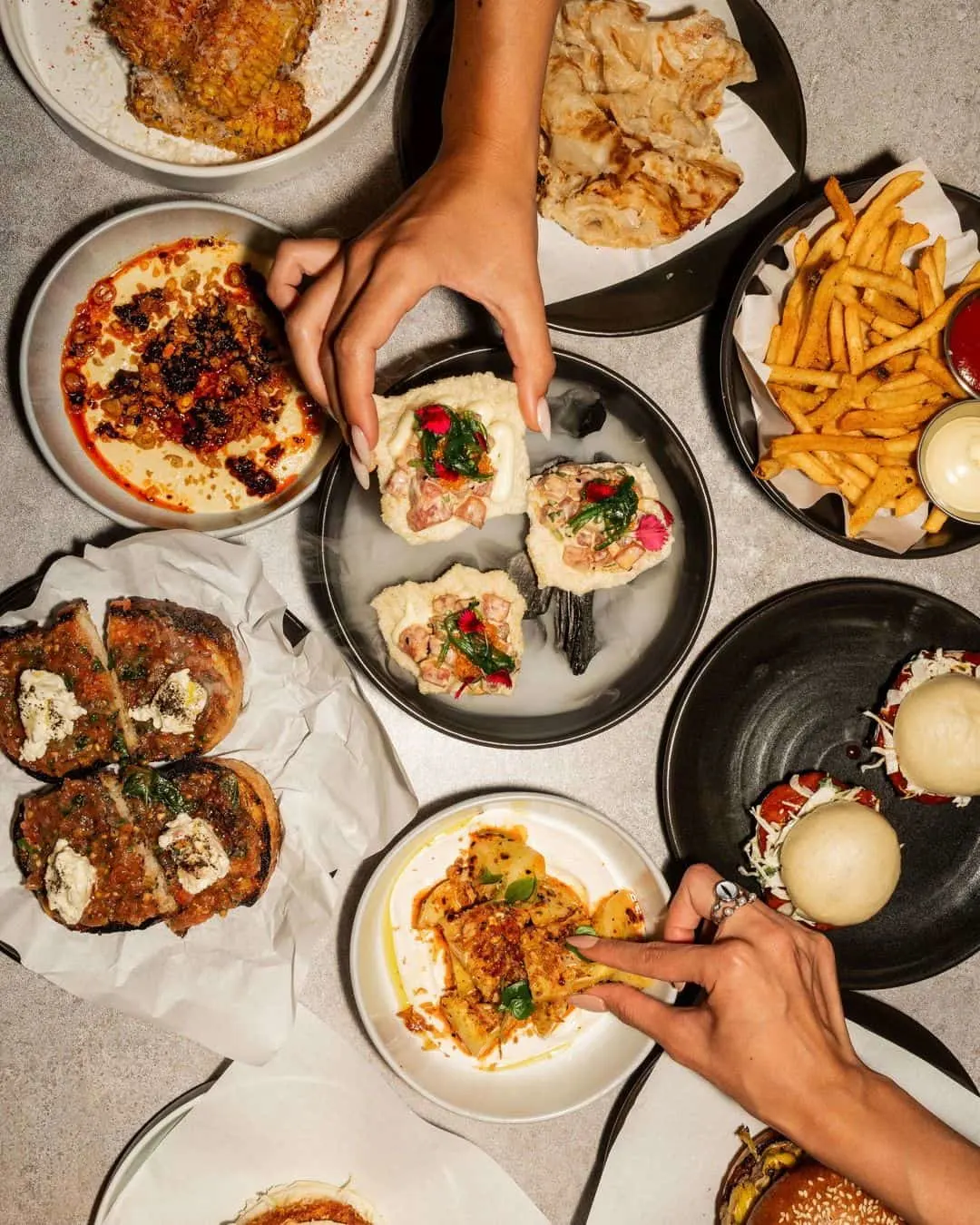 Bar food bites including whipped chickpea hummus, fries, bao buns and corn