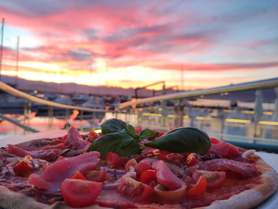 a pizza under a red sky by the mediterranean sea at al portocciolo restaurant in arbatax sardinia italy