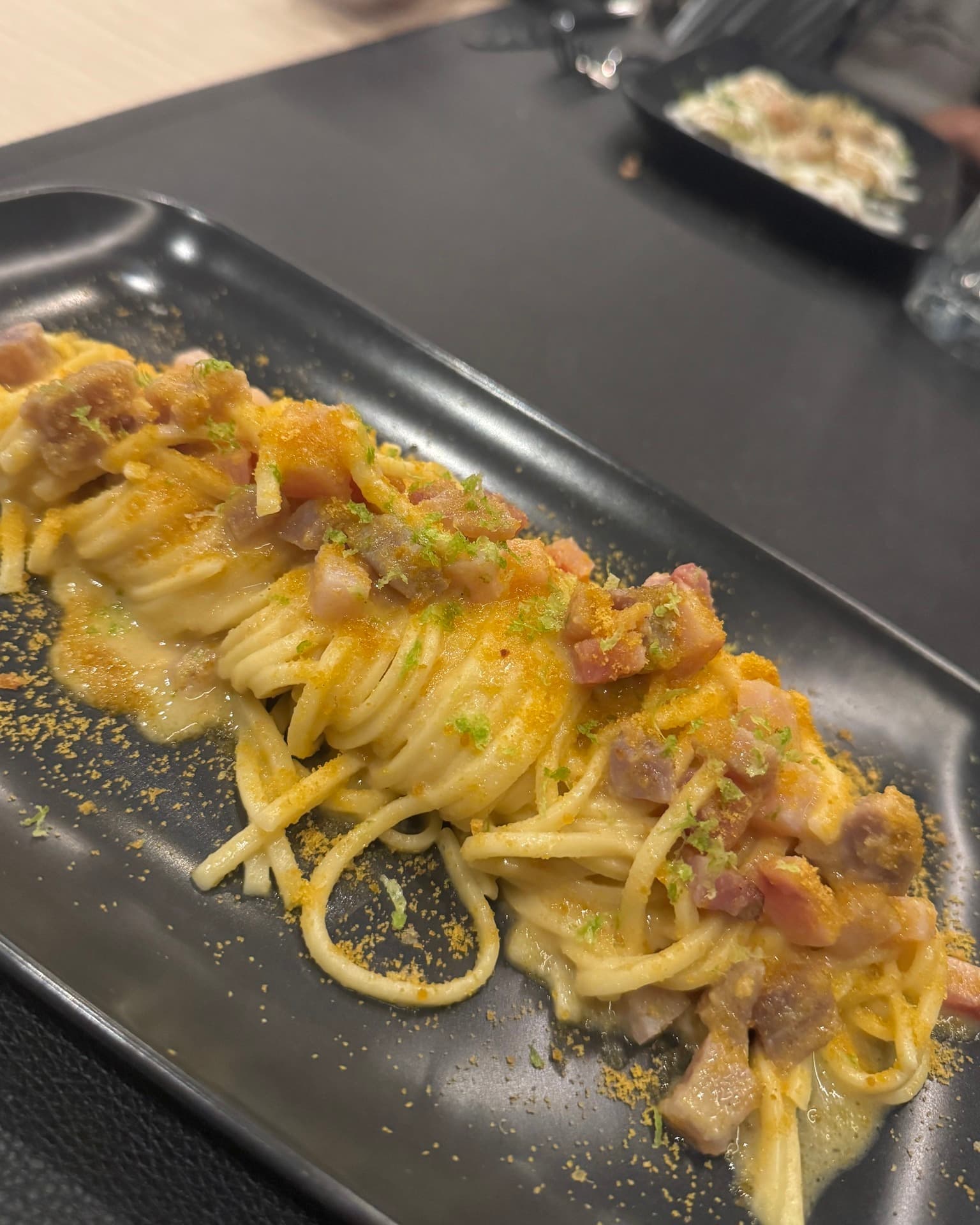 spaghetti carbonara on a black plate from nou restaurant costa rei sardinia