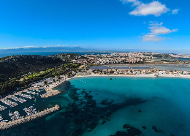 poetto beach and the mediterranean sea with a marina in the foreground and cagliari sardinia italy in the background