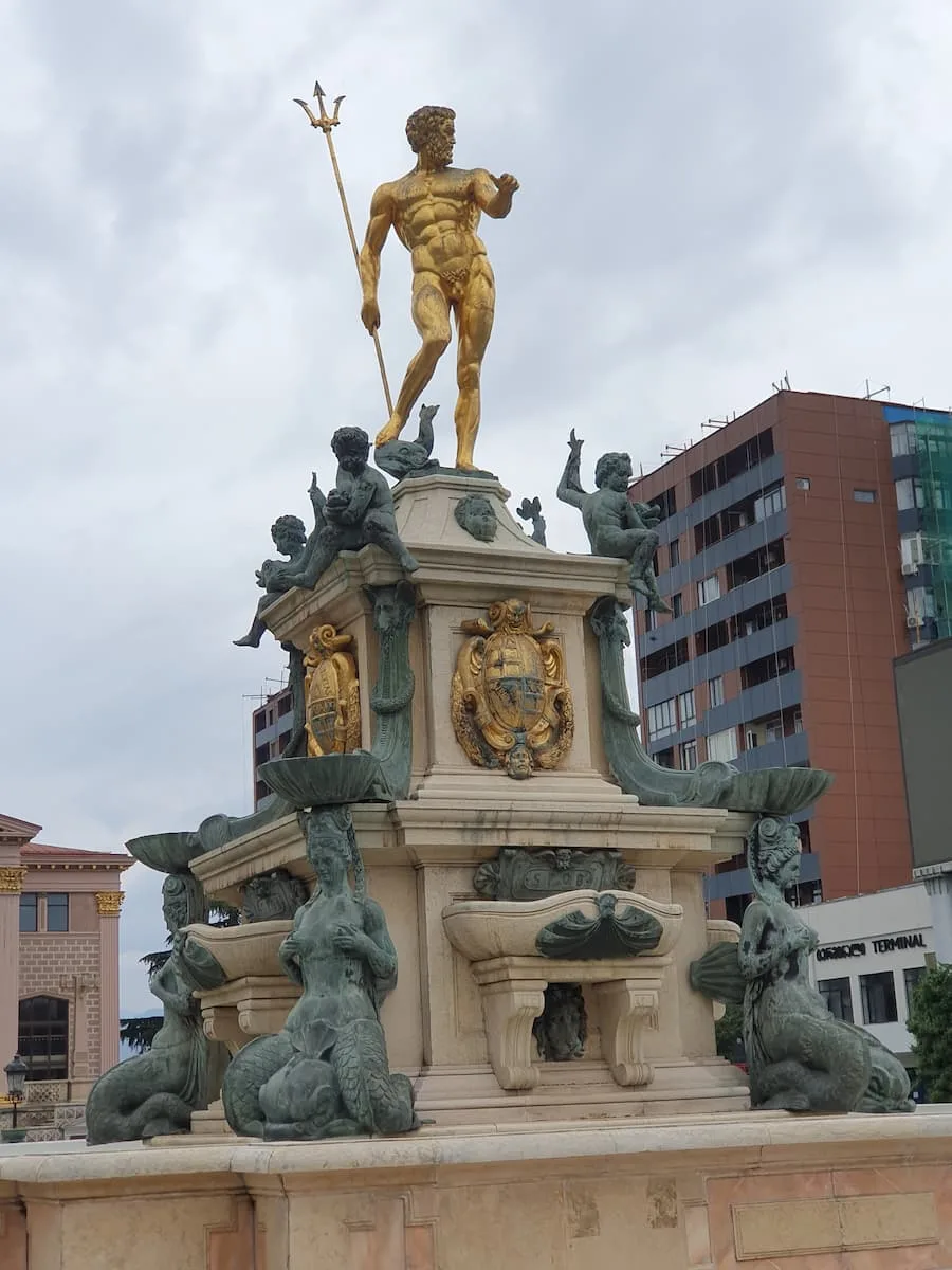 a gold statue of neptune in europe square batumi georgoa