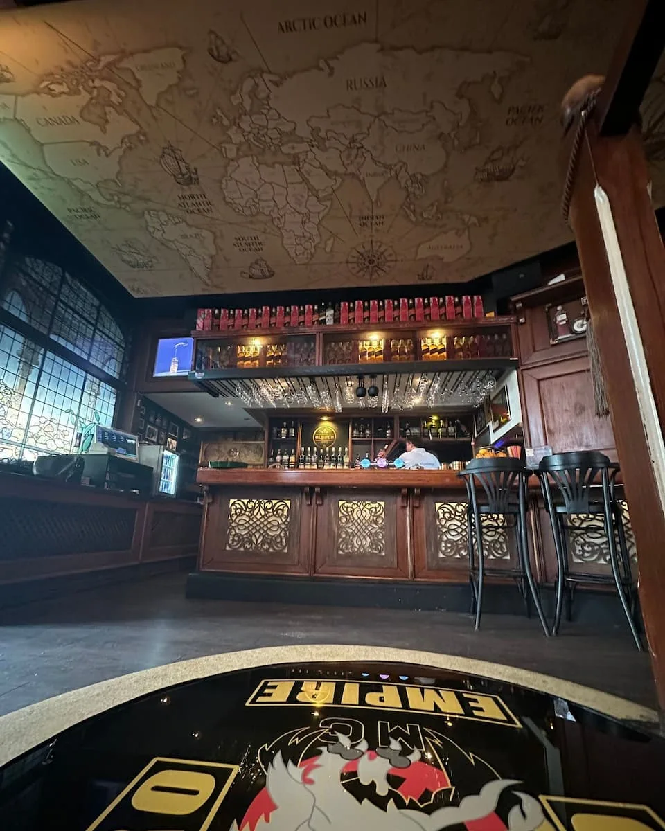a bar table with a motorcycle club emblem under a ceiling poster of a world map at old pub sarajevo bosnia