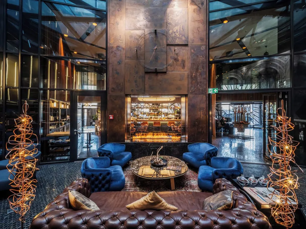 a wood clad fireplace and blue armchairs in the lobby of hotel clark in district I the best area to stay in budapest hungary
