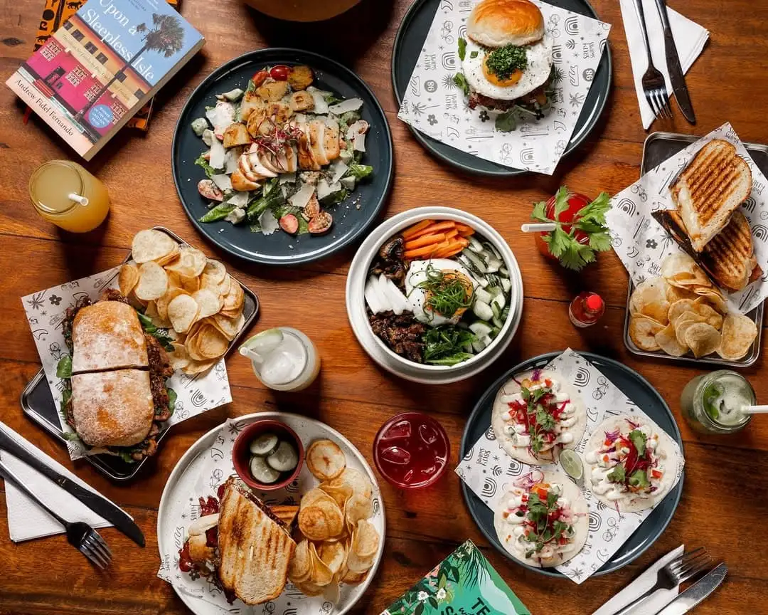 An array of dishes including tacos, chicken Ceasar salad, sandwiches