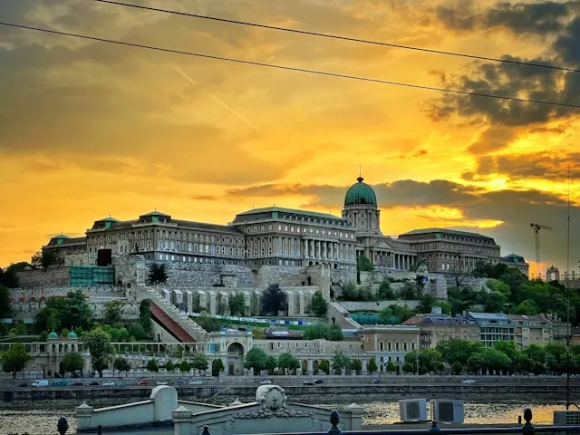 grand buda castle behind the danube river at sunset in budapest hungary