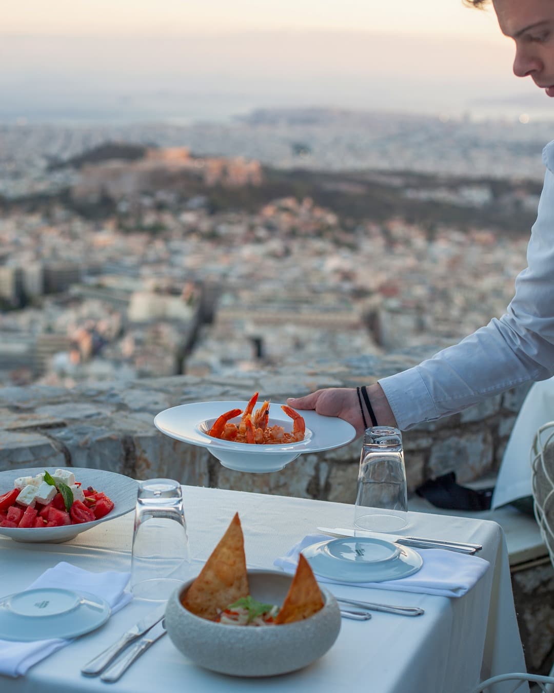 Dishes served at Orizontes Lycabettus, including greek salad and prawn risotto