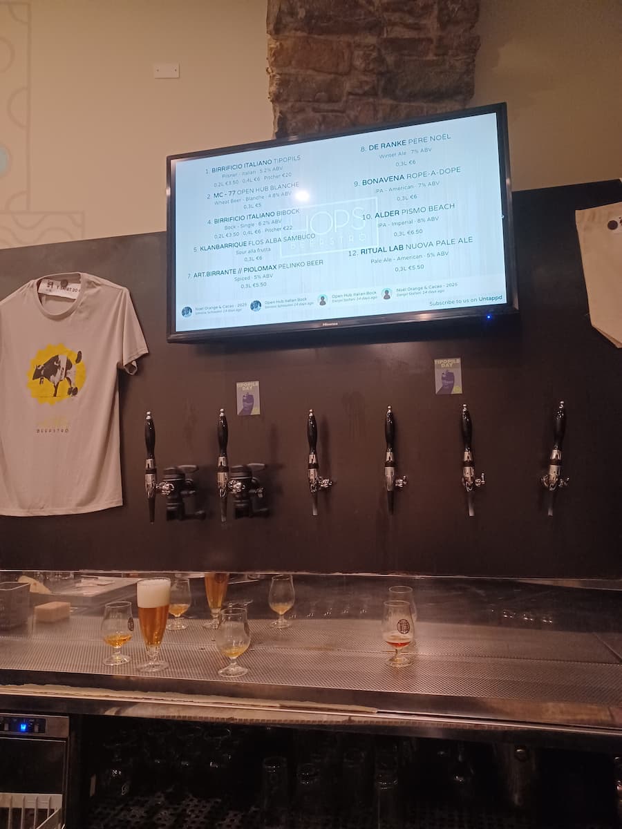 a tv displaying a drinks menu above beer taps at hops beerstro bar bistro in trieste italy