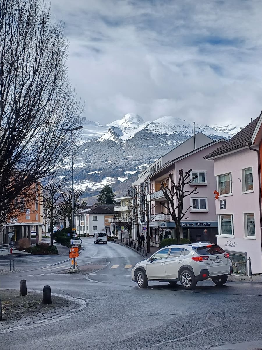 a car on a road with the alps mountains in the background in vaduz lichtenstein